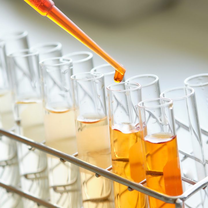 Glass dropper with vegetable oil being handled by an employee in the BBF lab