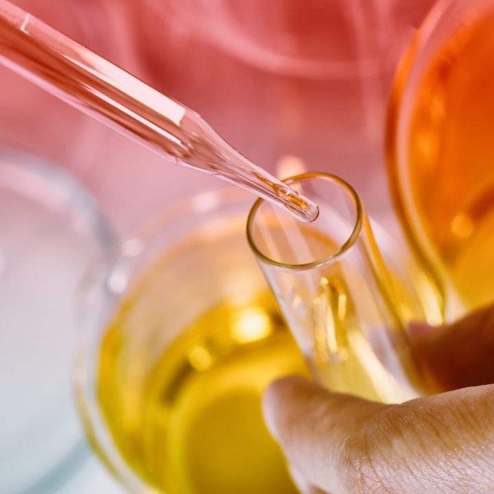 Glass dropper with vegetable oil being handled by an employee in the BBF lab