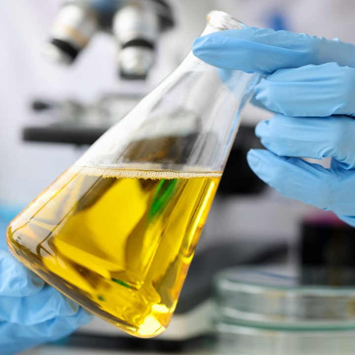 Glass bottle with vegetable oil being handled by an employee in the BBF lab
