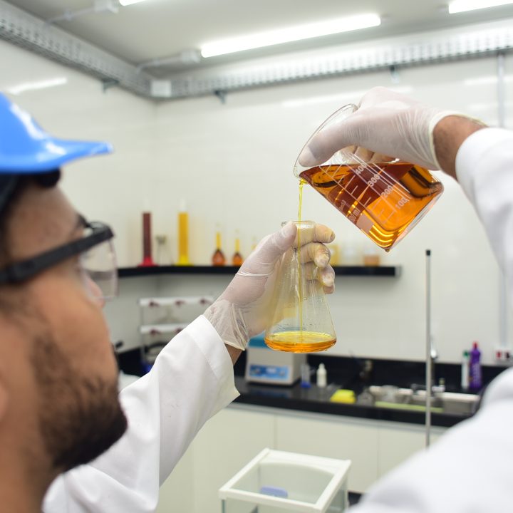 Employee in a laboratory at Grupo BBF handling a glass jar with vegetable oil