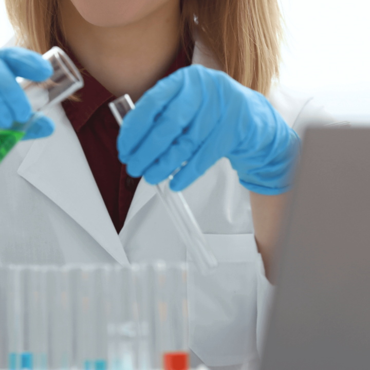 o: employee in a Grupo BBF laboratory handling glass bottles with chemicals